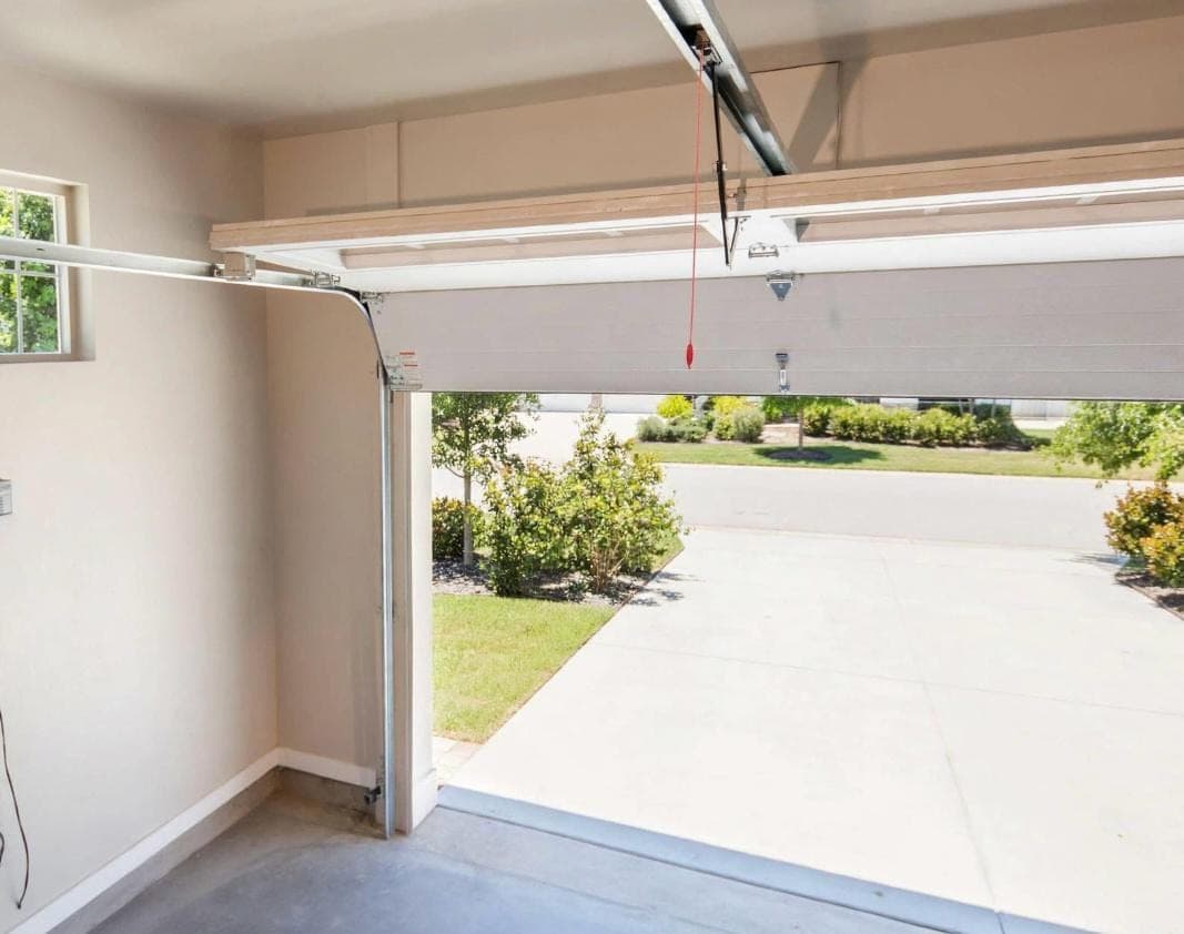 Inside view of a garage door's horizontal track, rollers, and red emergency release cord