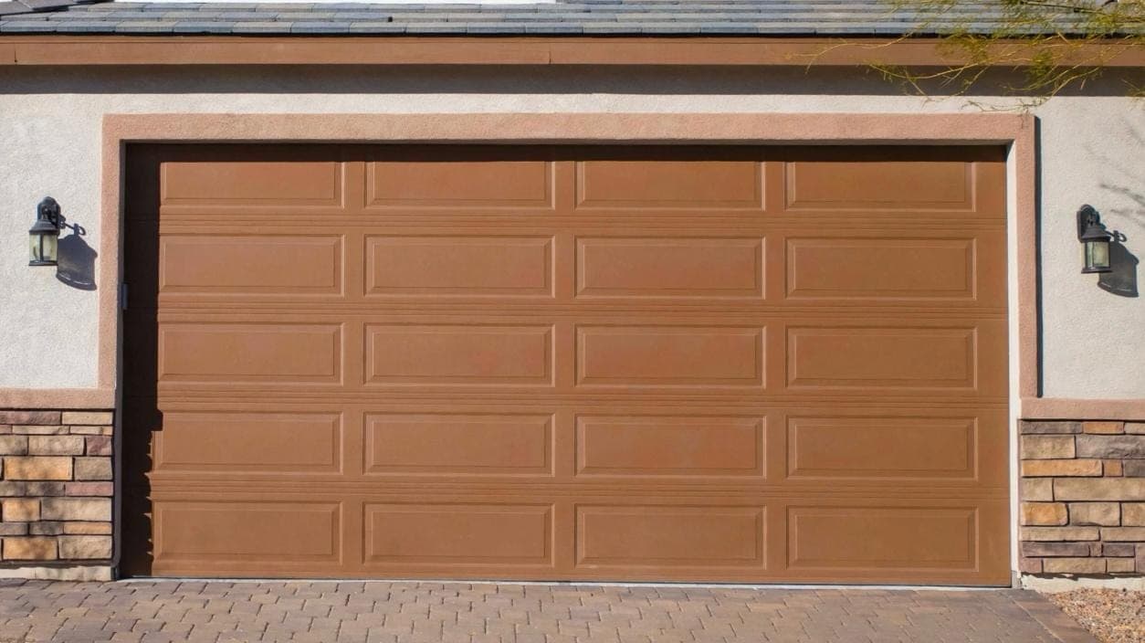 Brown long-panel garage door installed on a Las Vegas stucco home with stone accents and a paver driveway