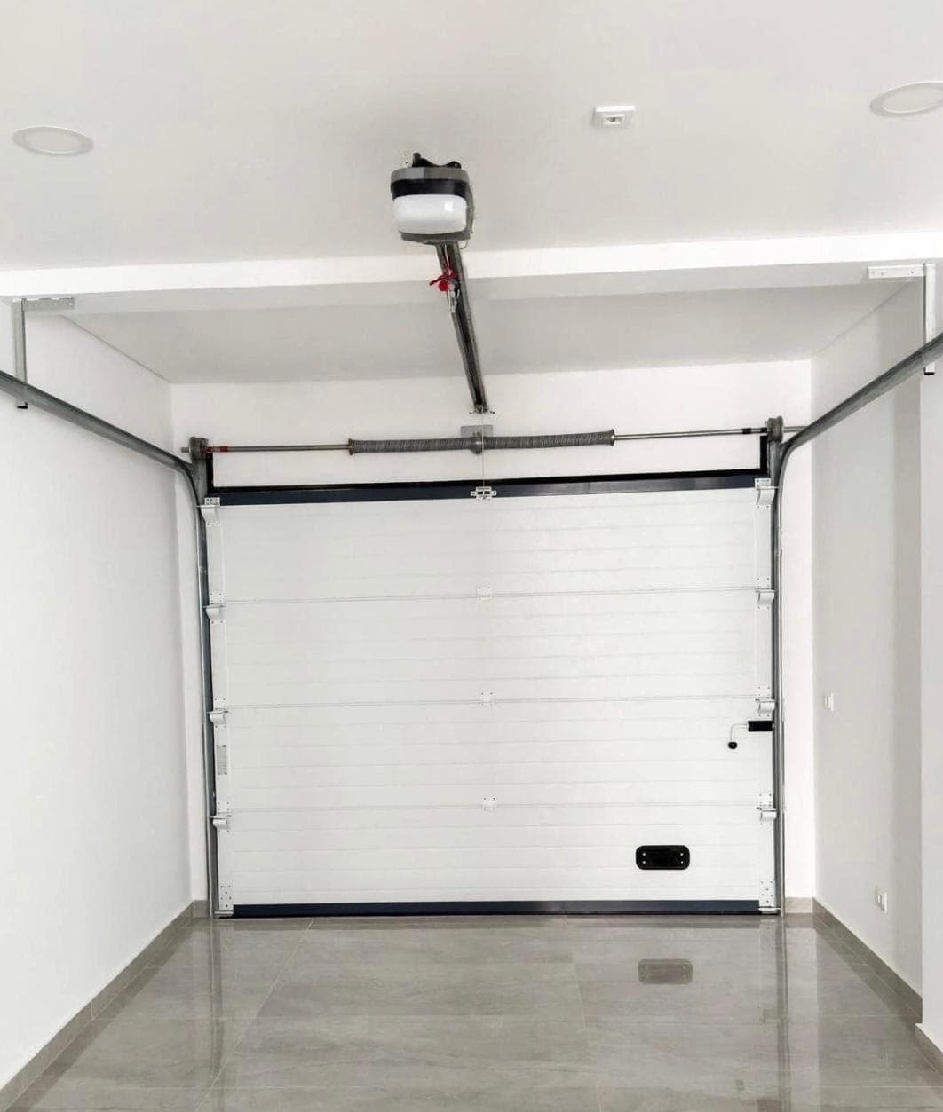 Garage door torsion spring, lift cables, and ceiling-mounted opener seen from inside a Las Vegas garage